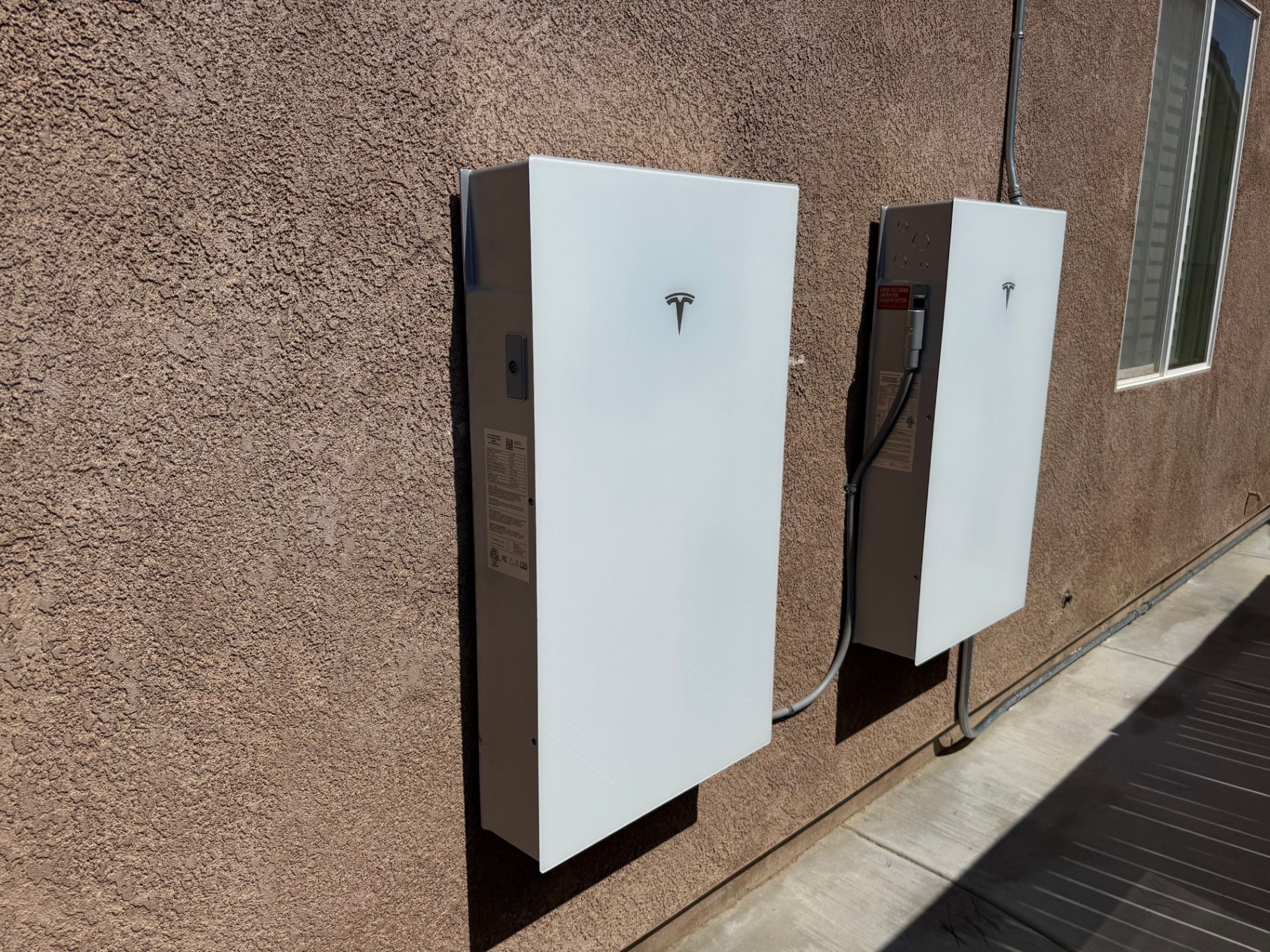 Two Tesla Powerwall batteries installed on the side of a home by Vibe Solar